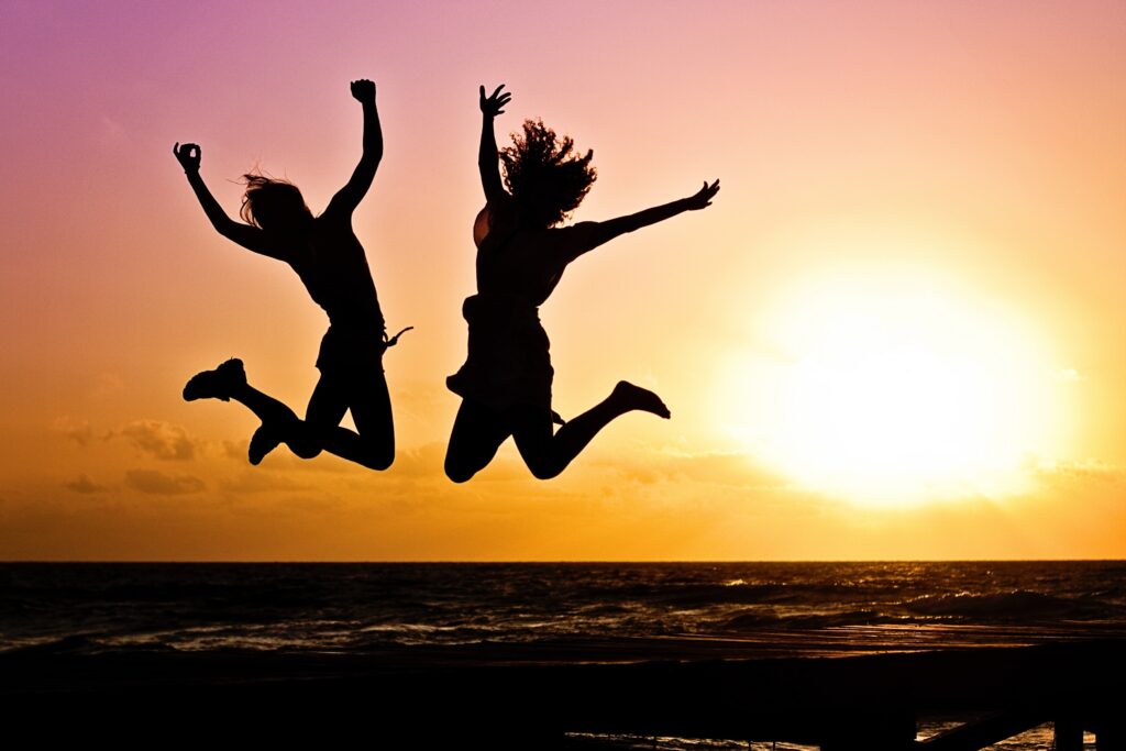 Happy people on the beach, symbolizing how creativity benefits your wellness and makes you happier.