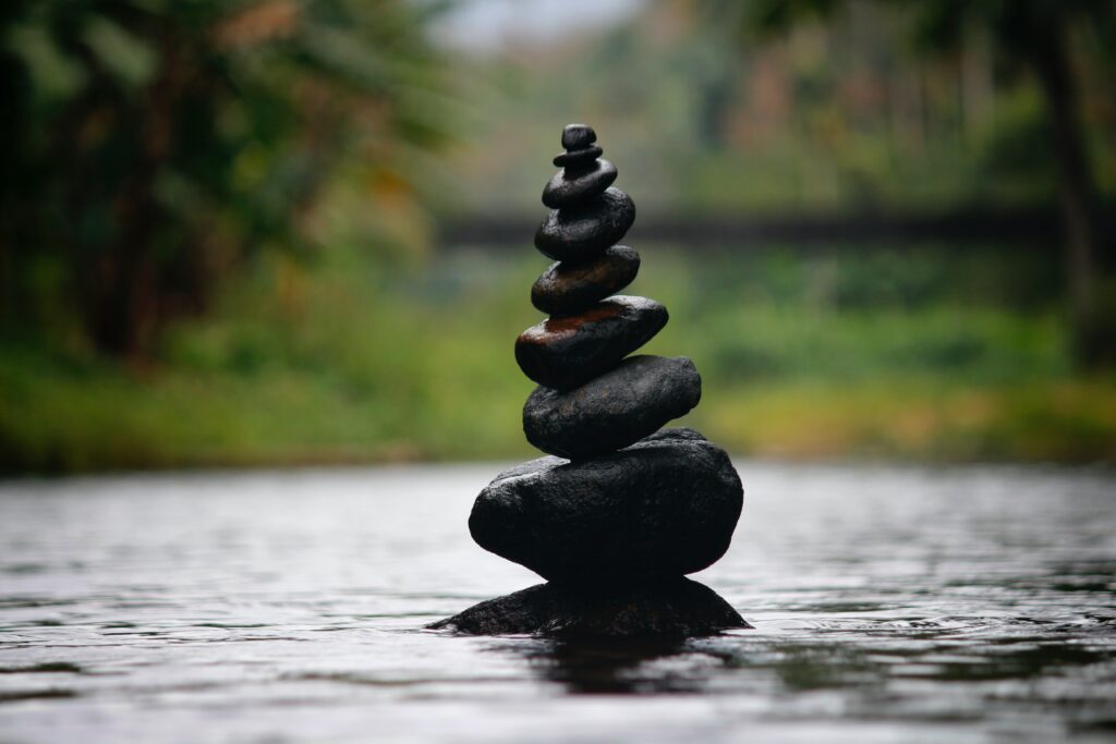 A stack of rocks on the water, representing how creativity benefits your wellness and encourages mindfulness. 