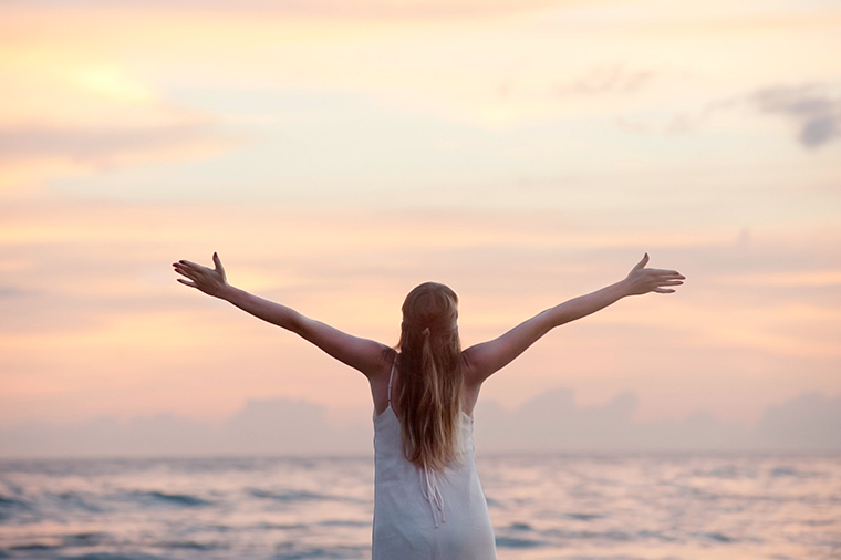 Gratitude journaling improves your mental health, represented by this woman on the beach. 