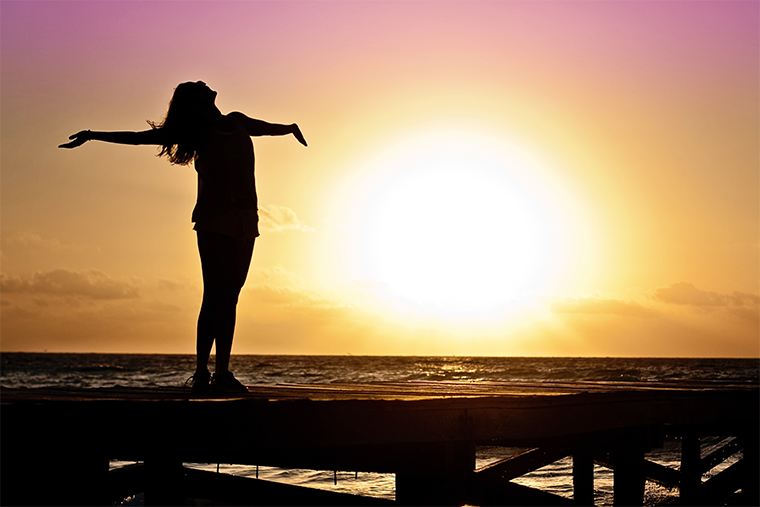 A woman embracing a sunrise, a result of a positive state of mind