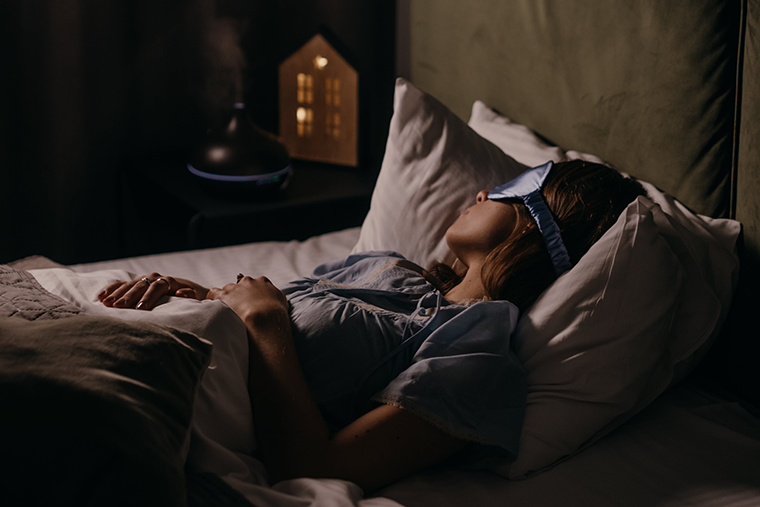 Woman Sleeping with an Eye Mask and dark room - both will help you get better sleep