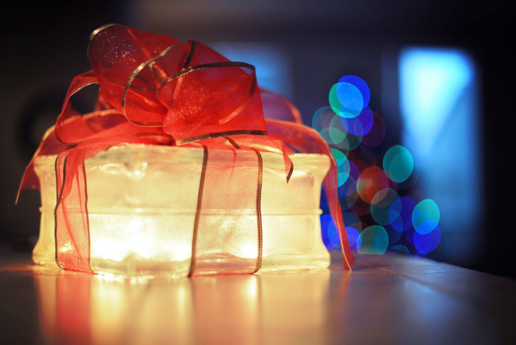 A lit-up glass brick, wrapped in a bow, symbolizing a meaningful holiday gift.