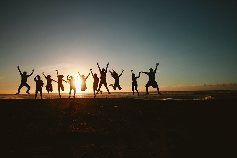 Happy people jumping on the beach, all spreading positivity and kindness